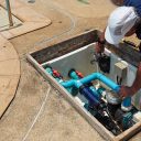 Technician fixing swimming pool water pump. Service and maintenance for swimming pool.